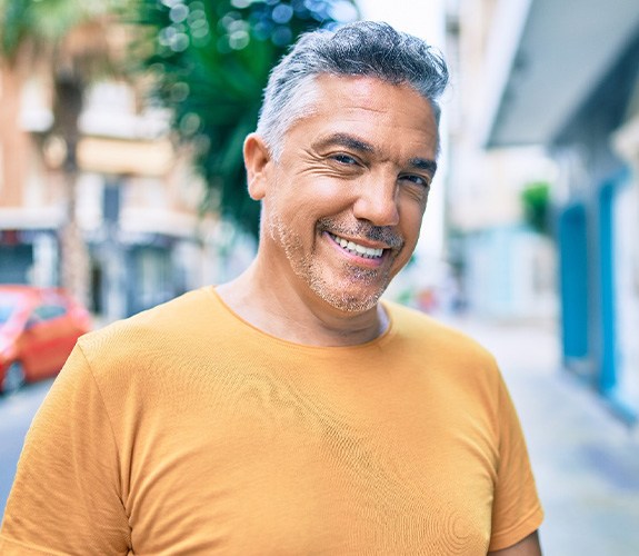 Middle-aged man outside showing off dental implants in Naperville