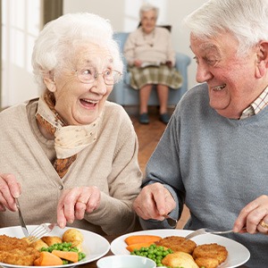 Older couple eating healthy meal while wearing dentures