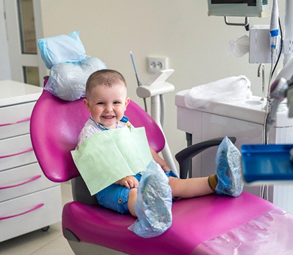 Young child smiling and sitting on dental chair