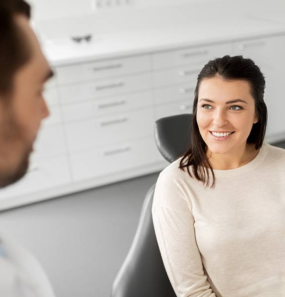 Woman in dental chair smiling at dentist