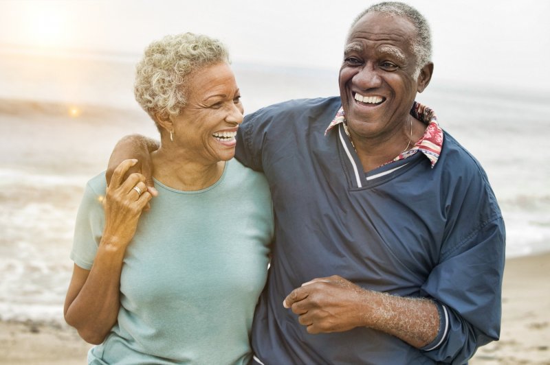 older man and woman on the beach smiling